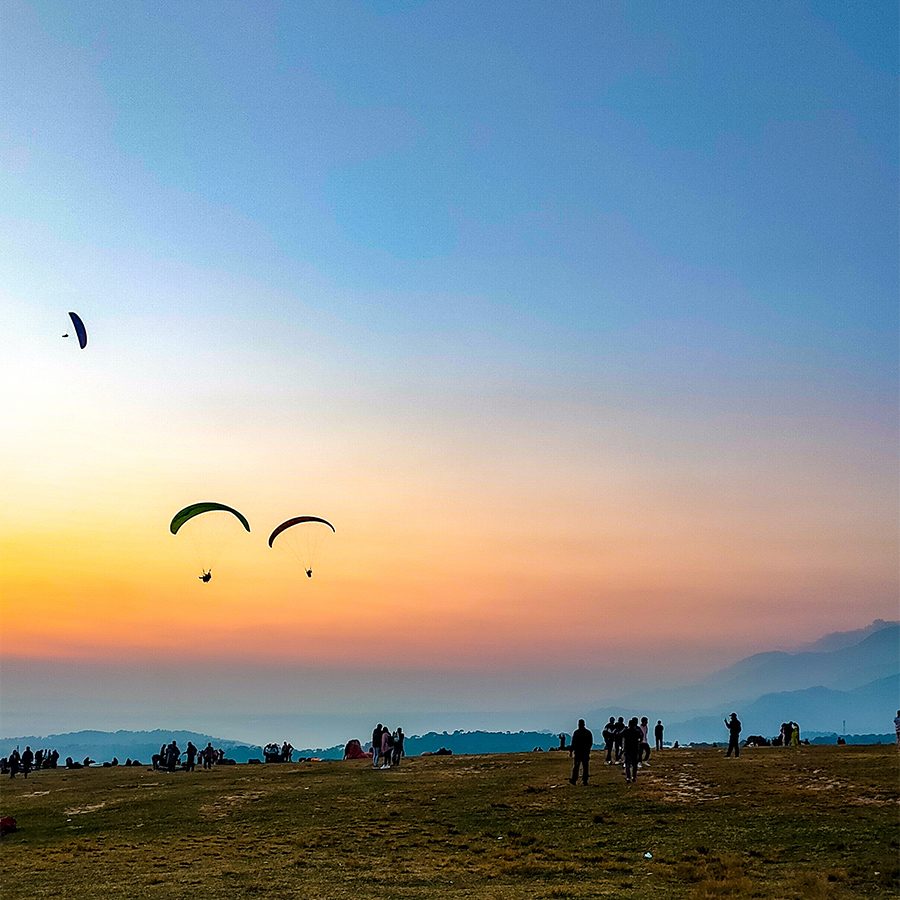 Beach at sunset with paragliders in the sky